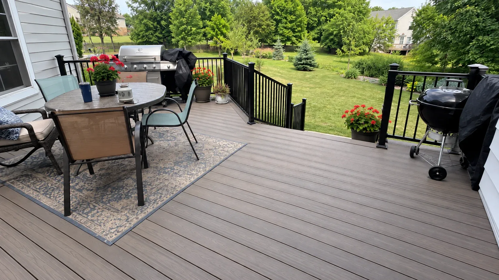 A composite deck with black aluminium railings at sunset, steps leading up to an upper level beside the house