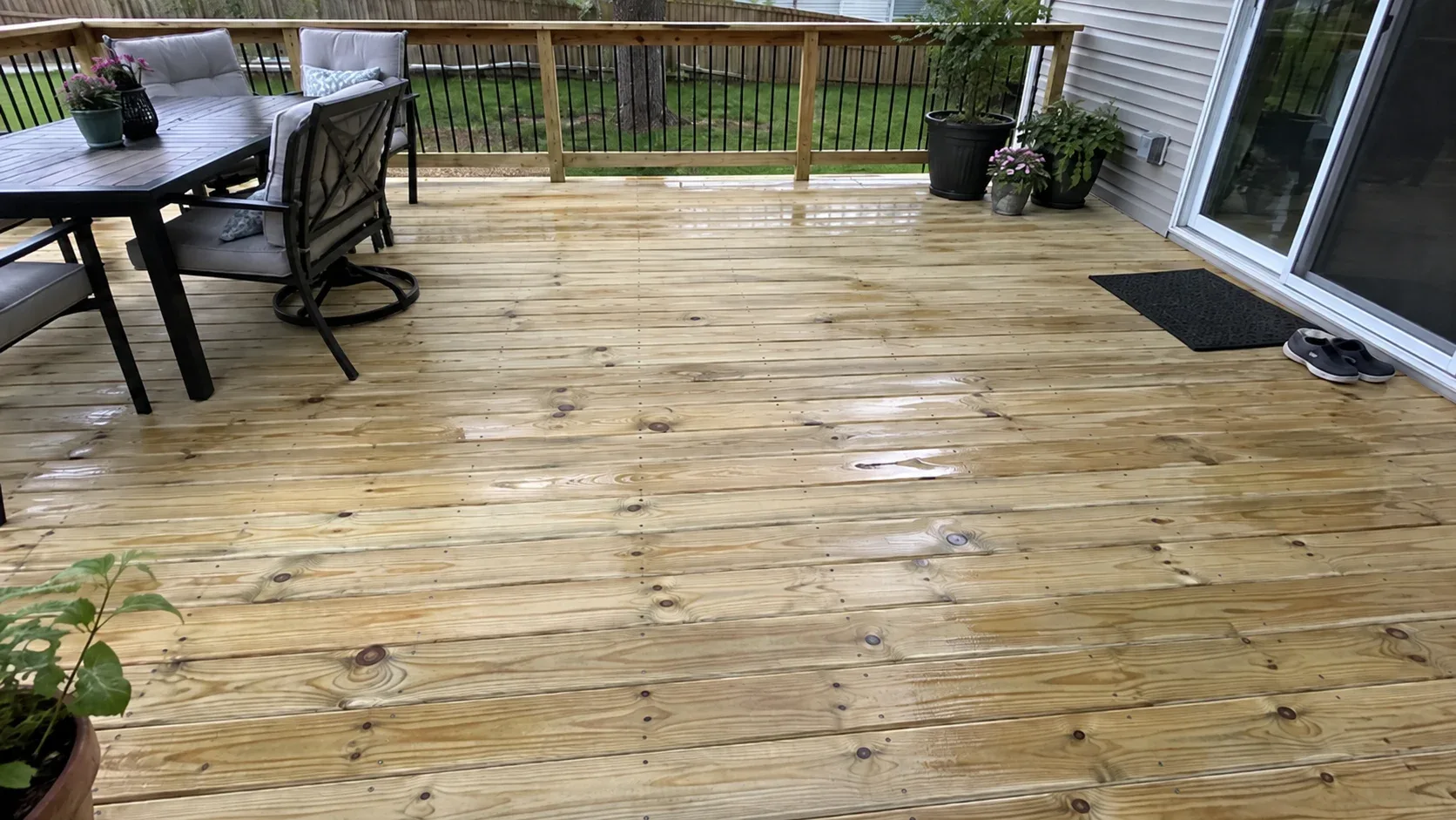 Freshly laid pressure treated pine decking with knots, a green treatment tint and rows of countersunk screw heads, a tape measure at the edge